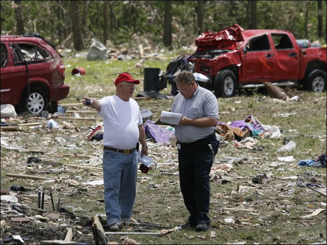 CTY  tornadofolo07p William White, left, speaks to his insurance agent Rick Anderson, from USAA, right, to asses the damage to his home and property that was destroyed by the tornado. White's truck, behind, was blown into their backyard.