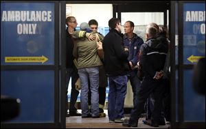 Firefighters and others wait in the emergency room entrance at Mercy St. Vincent Medical Center, their two injured colleagues had been taken earlier in the day. The two killed were a 15-year veteran and a firefighter sworn in September.