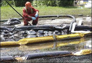 A worker monitors water in Talmadge Creek in Marshall Township, Michigan, near the Kalamazoo River, in July, 2010. Crews were attempting to contain oil that spilled from a ruptured pipeline.