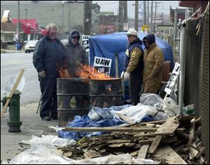 Mike Sweeney, Mark Fay, Jim Spetz, and Mike Webster, from left, huddle around a fire in a trash bin outside Superior Spinning & Stamping on Front Street, where the United Auto Workers union is on strike.