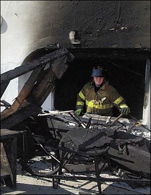 A Toledo firefighter clears debris from the area of the yacht club that was hit by a morning electrical fire.