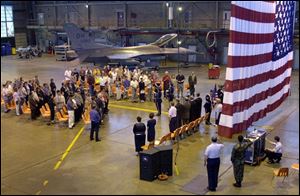 New citizens, in an Ohio AIr National Guard hangar, honor the American flag with the singing of the National Anthem.