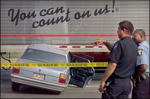 Maumee Lt. Mike Fortney, left, shows the Oldsmobile that ran into a semi to end an auto chase on the Anthony Wayne Trail.