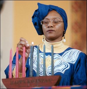 Pauline Kynard lights a candle in a kinara, or candleholder, during a 1999 Kwanzaa program.