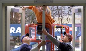 ROV removing 01 - 011402 - Jeff Stone, up top, concentrates on figuring out how the center post of the door in the new BGSU student union comes out as Field Borton, left and Frank Melchor, co-workers with Gem Industries help out. The post had to be removed so the mobile lift that Stone was using could be moved inside the newly remodled building. The Blade/Allan Detrich