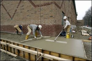 Roger Born, Jim Kennaw, and Keith Hardwick, from left, of Thomas & Marker Construction Co. finish the sidewalk outside the middle school.