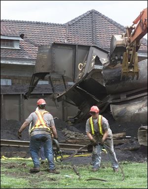 Crews remove debris near where a coal car hit the town's former passenger depot.