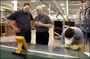 Gov. Bob Taft listens to Jim Flanary, of First Solar LLC, as Dewayne Bridge does a quality check on a solar-panel part at the $16 million production facility in Perrysburg Township.