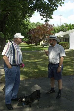 `I want to stay here. I'm not going to move. This is my neigh- borhood,' says Dr. Nick Russo, right, talking with Bill Carlisle while Mr. Carlisle walks his dog, Bessie. The two are neighbors on Montebello Road, where University of Toledo students live.