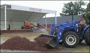 Volunteer Glenn Keck works on landscaping the stage area for this year's fair, which begins Sunday.