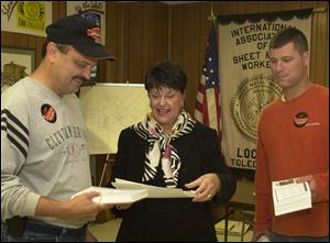 Sandy Isenberg dispenses literature to supporters Craig Mead, left, and Nick Dukeshire at a union hall.