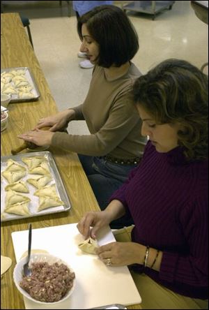 Antoinette Moubayet rolls dough as Linda Yazji puts meat filling on dough and pinches the sides together before meat pies are baked at St. Elias Church.