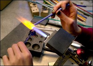 Katie Kinnel, 17, of Ottawa Hills High School, works with glass in her bead-making class in the Toledo Museum of Art.