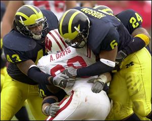 UM's Carl Diggs, left, and Victor Hobson stop the Badgers' Anthony Davis, who gained 154 yards on 26 carries.