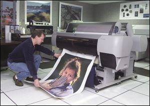 SFC employee Ken Celski examines a 3-foot-by-5-foot print as it comes rolling out of a processing machine at the Toledo plant. The company employs 35 people.