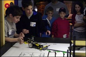 From left, junior high pupils Alex Silverman, 10, and Chad Liber, 11, both of Stone Hebrew Academy of Toledo, race robots through a miniature city built from Legos. The robots were required to perform certain tasks in COSI competition yesterday.