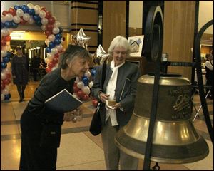 Dorothy Surheide, left, and Leah Heimbeck admire the Lucas County bicentennial bell on display at the Main Branch of the Toledo-Lucas County Library.