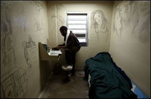 Jermaine Edwards reads a paper in a cell at the Lucas County Jail. The cell was decorated by the previous inmate.