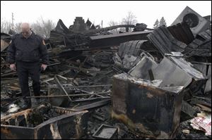 Joe Tuckey, Tecumseh fire chief, pokes through the ruins of Fabricare Dry Cleaners & Coin Laundry at 117 Herrick Park.