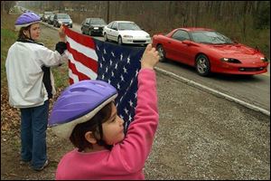 Casey Lamson, 10, left, and Kelsey Lamson, 9, hold a flag as Pvt. Juan Garza's funeral procession passes by on Sterns Road.