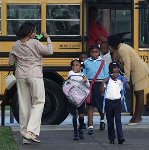 CTY TPS12P 4 8/12/03 PHOTO BY LORI KING Stephanie Smith takes a photo of her daughter, Kayla, pink and grey bookbag, as the kindergartner gets off the bus for her first day of school at Old West End Academy.