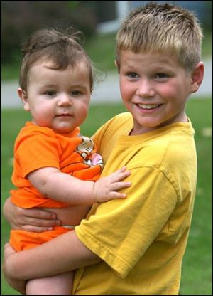 Freedom Higgins, 8, holds his brother, John, 8 months, in the family's front yard.