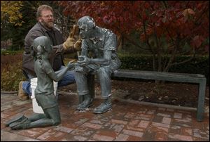 CTY GIRL06P 1 11/6/03 PHOTO BY LORI KING Ken Thompson, of Flatlanders Sculpture Supply, Blissfield, MI, gives the old man in the Seasons sculpture a bath while the little girl watches. The man and girl were reunited after she was vandelized and taken away to be fixed.