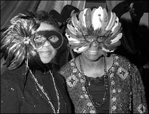 Jeanette Bradley, left, and Junie Williams get in the spirit of the Fair Housing Center's Mardi Gras Fat Tuesday party.