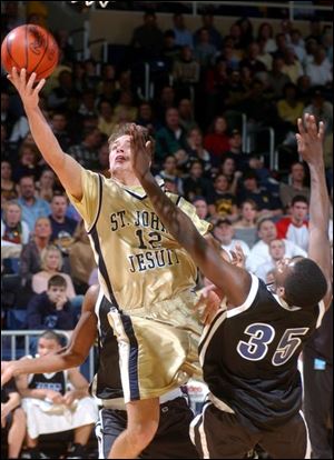 Duke Keller of St. John's goes to the basket against Cleveland Rhodes' Joe Roberts. The Titans (21-4) play Olmsted Falls (22-2) tomorrow for the regional championship.