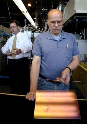 Tom Kennedy displays coated glass as Stephen Weidner explains the process to visitors.