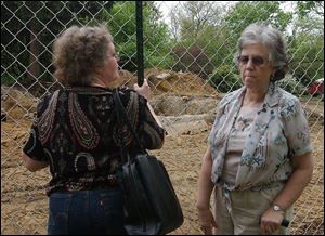 Gaye Gindy, left, and Jackie Konwinski spent time yesterday at the site of the Lathrop House. Behind them is what's left of the basement where runaway slaves reportedly hid.