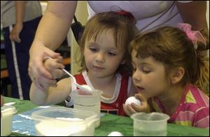 NBR  Alisa Shelt, 3, of Wauseon, Ohio adds salt to a beaker of water to enable the golf ball she is holding to float. It was one of the science experiments that were offered by the outreach department of Ann Arbor, Michigan's 