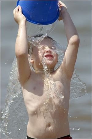 ROV swim 02 - Devin Mervine, 6, son of Brenda Mervine of Castalia, grimaces as he dumps water over his head at the Port Clinton public beach after getting water in his eyes. The warm weather had the beach quite crowded. Allan Detrich/The Blade