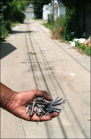 A resident holds unexploded fireworks he found in the alley behind Pearl Street.