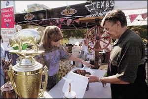 Perrysburg residents Stacey Clink and her father, Dave Swiater, sample the fare during the Northwest Ohio Rib-Off held in Promenade Park. The event continues today.