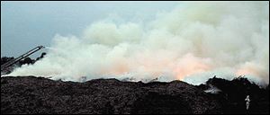 A firefighter, at right, is dwarfed by the Stickney Avenue blaze.