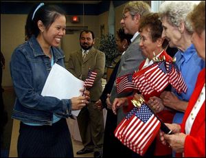 Angie Andrews, left, a native of Thailand who became a U.S. citizen at a ceremony at the Greater Islamic Center of Toledo, is greeted by women of the American Legion.