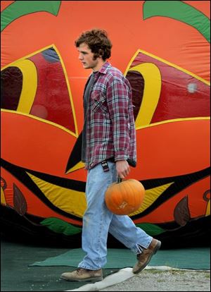 ROV pumpkin 01 - Mike Glenn, an employee of Schweizer's Fruit Farm in Oregon, Ohio, carries a pumpkin as he re-stocks the shelves for the fall season. Allan Detrich/The Blade