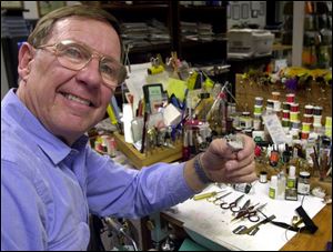 Chris Helm, of Toledo, holds one of his most popular fishing flies, a deer-hair mouse fly tied in his basement workshop.