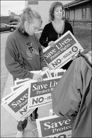 Tosha Carman, left, and Myndi Milliken collect yard signs that urge voters to reject amending Toledo's smoking ban. 