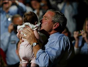 President Bush kisses a baby at a campaign rally in the Canton Palace Theatre, where he called for a 'common-sense approach' to make sure health care is available and affordable.