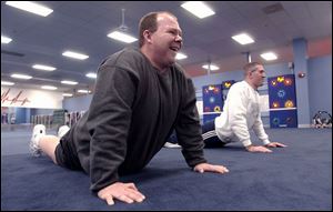 Jim Crocker, left, stretches as part of his workout routine with trainer Joey Shinaver. 