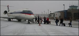 Passengers file onto a Delta Connection airplane at Toledo Express Airport for a flight to the Cincinnati airport yesterday.