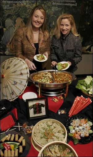 Linsey Ansberg, left, and Jenny Mitchell sample Asian Lettuce Wraps, which will be served at Toledo After Hours.