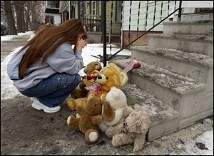 Jasman Johnson prays after putting flowers and a stuffed animal outside the house where a fire killed a 4-year-old child.