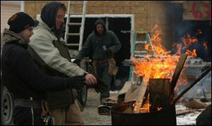 ROV hand warmer From left: construction workers Josh Guilda and Chuck Comer warm their hands and gloves with a barrel fire during a break from the cold while building a house on Hill Ave. in Toledo Friday, Feb. 11, 2005. They are from C. Comer Construction. Chuck is the owner. The Blade/Lori King