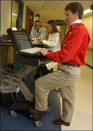 Dr. Kelley Shultz, assistant director of inpatient pediatrics at Mercy Children's Hospital in Toledo, uses a mobile computer to keep track of patient records. The device increases access to patient information, both in and out of the hospital.