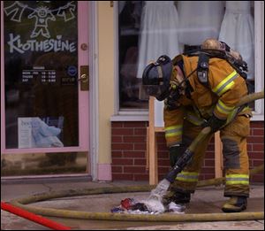 CTY perrysburg fire 1 A firefighter hoses down burnt clothing on a downtown Perrysburg, OH sidewalk where an upstairs apartment caught fire Wednesday, Feb. 16, 2005. The Blade/Lori King