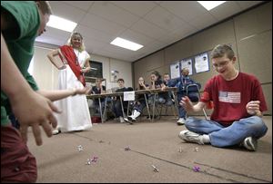 NBR olympic D -- Dustin Carey, left, and Andy Brubaker, right, compete in a game of jacks as social studies teacher Bonnie Urso supervises the competition during the 7-2 Olympics at Springfield Middle School. Seventh grade students were competing Friday, 03/04/05, in such events as chariot races, Olympic tongue twisters, sticky ball, ball in a basket, bubble gum blowing and other events, after having studied ancient Greece. The Blade/Andy Morrison