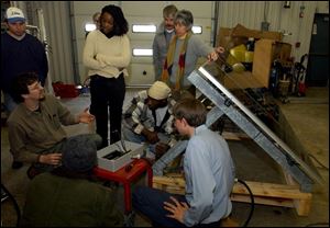 CTY solar11p 2 .jpg  Geoff Rich (kneeling on left) instructs on the wiring of a portable solar panel at Owens Community College Workforce Development Building on Tracey Road in Perrysburg Twp., OH. The Blade/Lisa Dutton